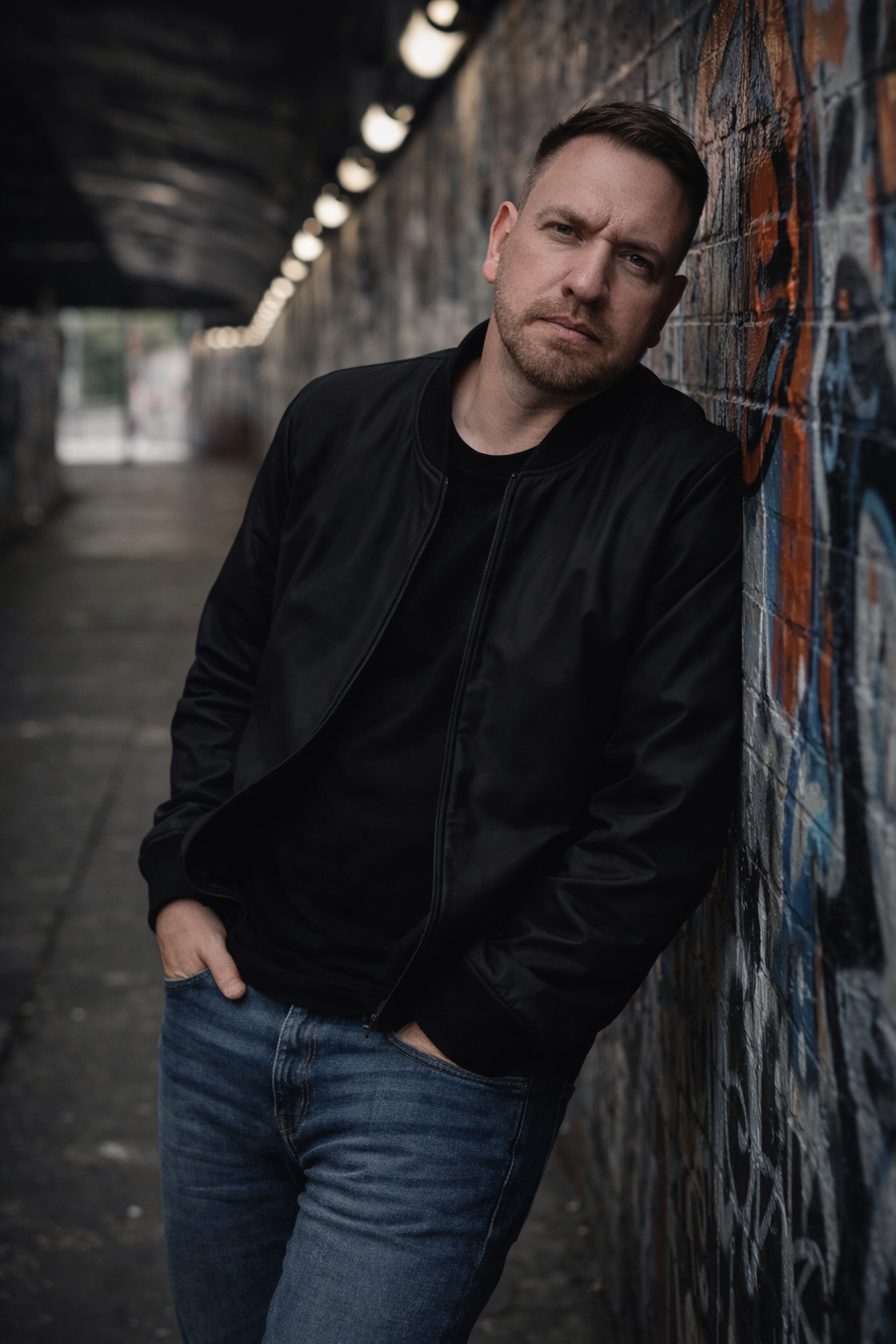 Darrell Lee leaning against a graffiti wall